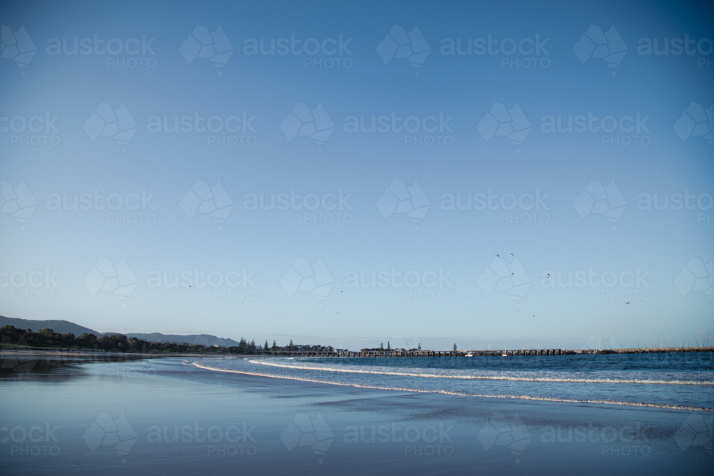 Waves rolling in on Coffs Harbour Beach with jetty in the distance, NSW Australia - Australian Stock Image