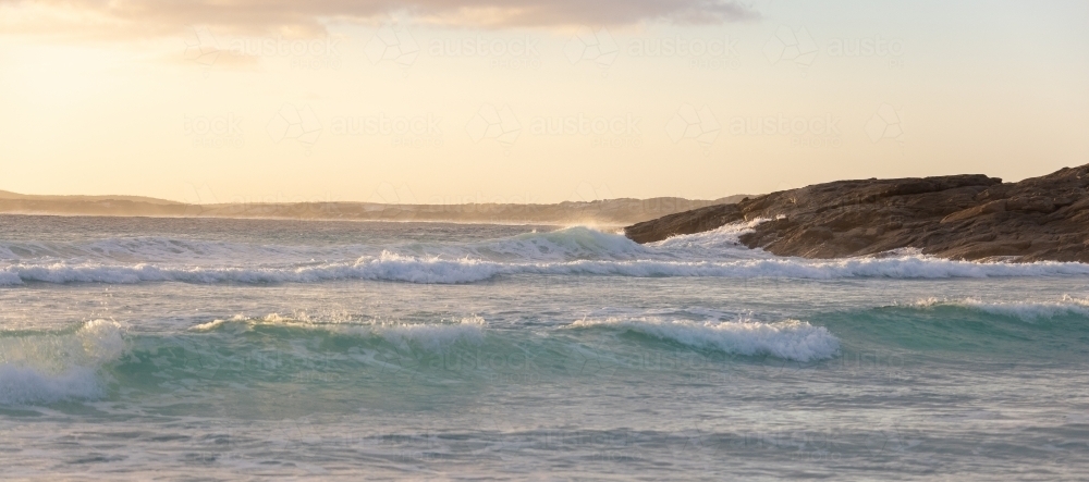 waves rolling on to rocky headland on the south coast - Australian Stock Image