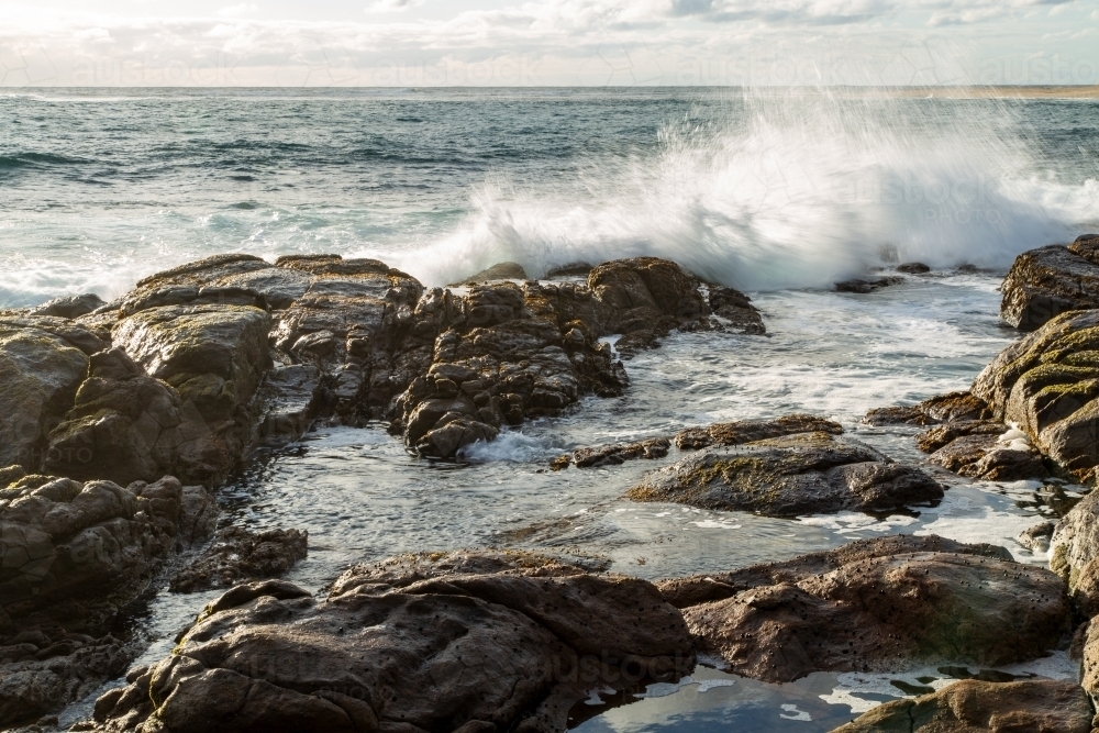 Waves splash against a rocky shore. - Australian Stock Image