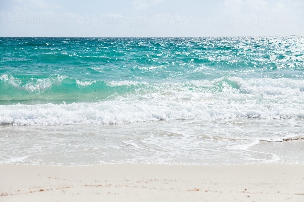 Waves wash up on white beach sand - Australian Stock Image