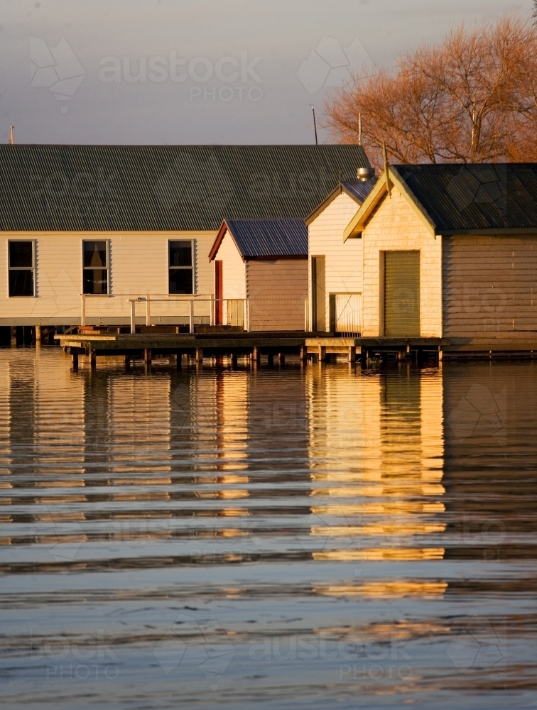 Weathered boatsheds and reflections on lake - Australian Stock Image