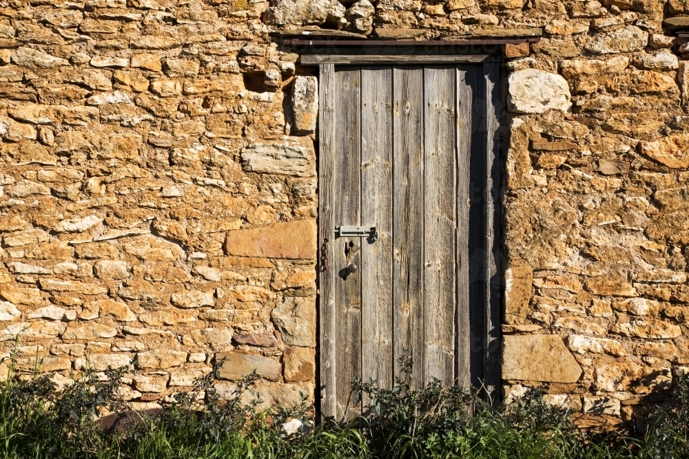 Weathered door in stone wall - Australian Stock Image