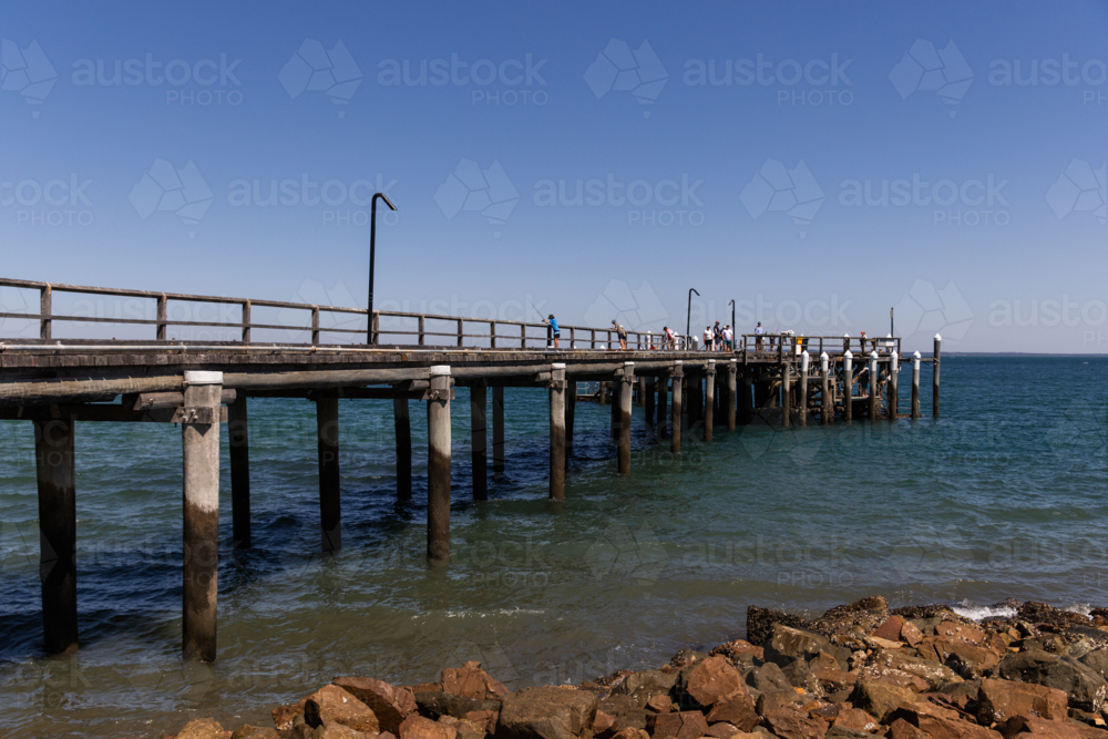 Image of weathered timber jetty on a calm blue sky day - Austockphoto