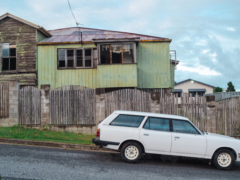 Weathered two‑storey house with station wagon outside - Australian Stock Image