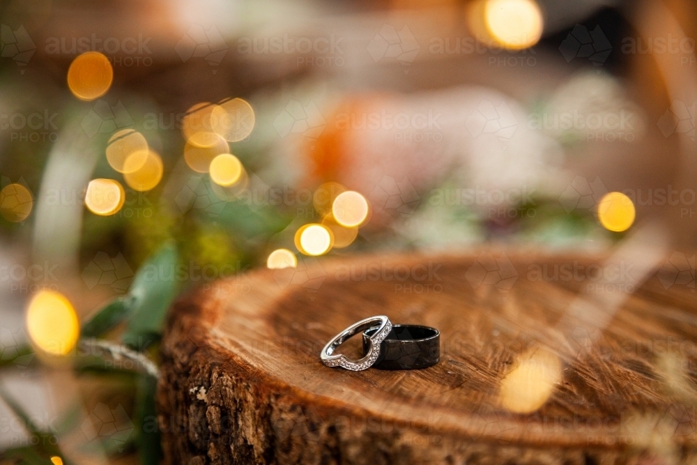 Wedding bands for marriage ceremony on wood round with bokeh lights - Australian Stock Image