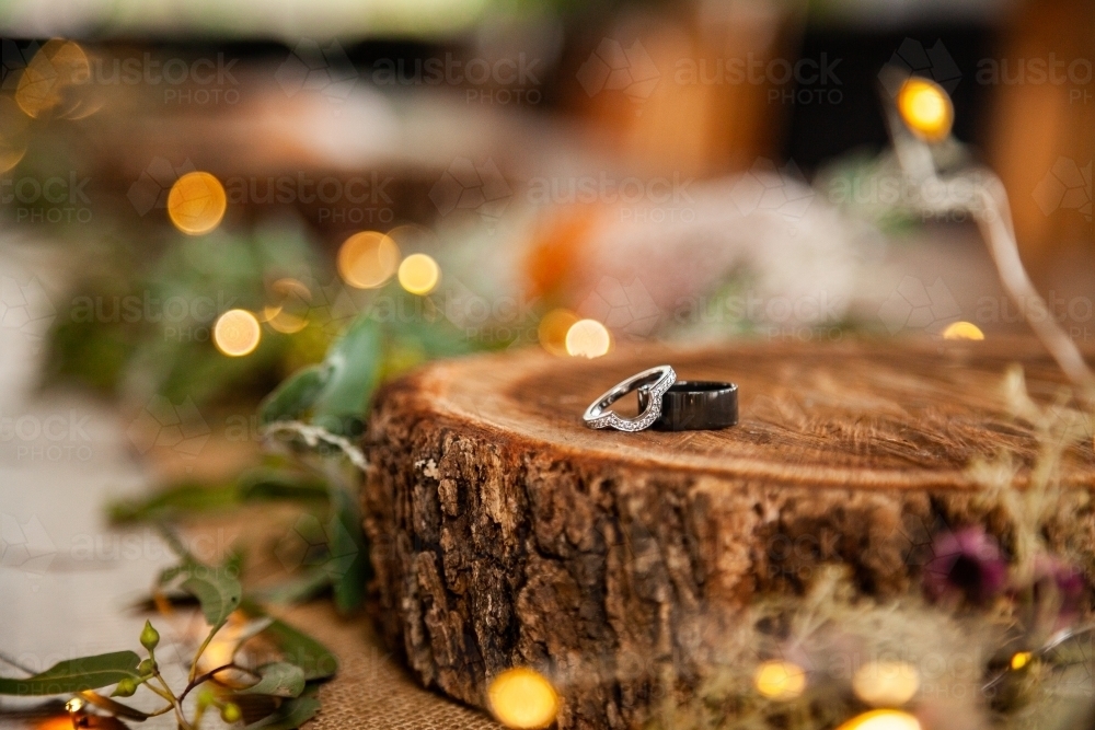 Wedding bands for marriage ceremony on wood round with bokeh lights - Australian Stock Image