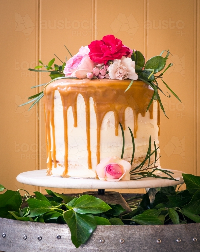 Wedding cake with fresh flowers and caramel drip - Australian Stock Image