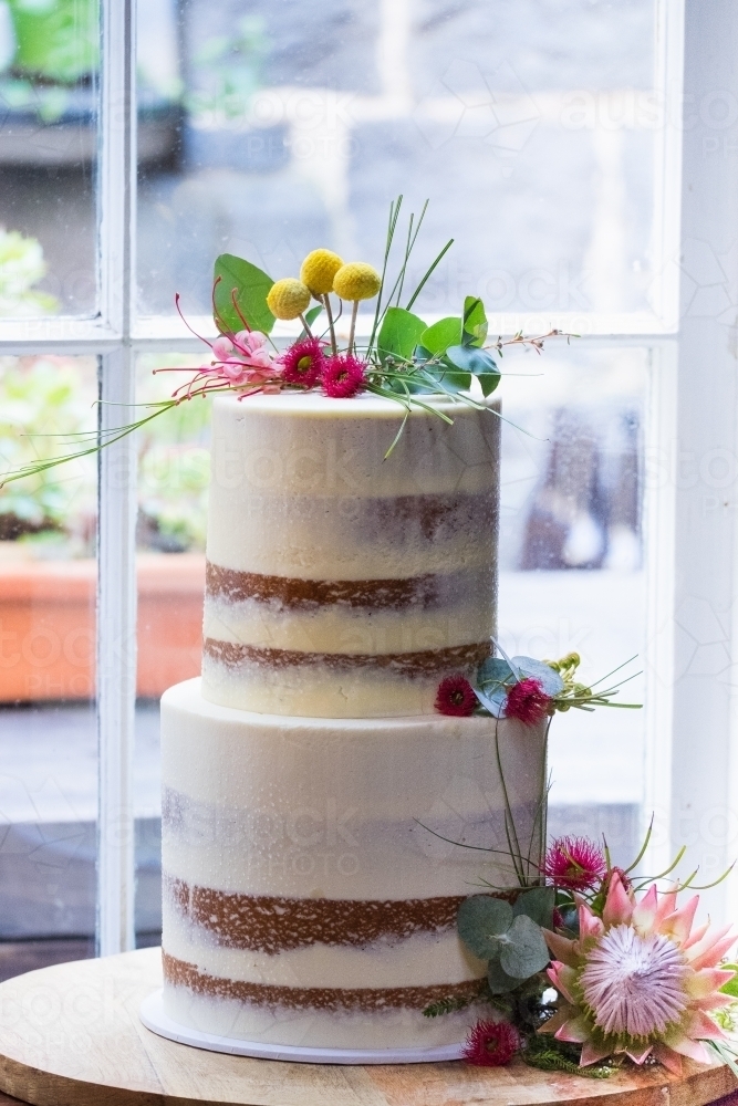 Wedding cake with native flowers in a window - Australian Stock Image