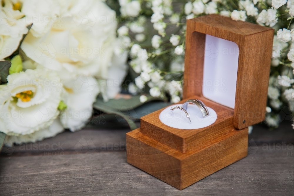 Wedding rings in wooden box with bouquet - Australian Stock Image