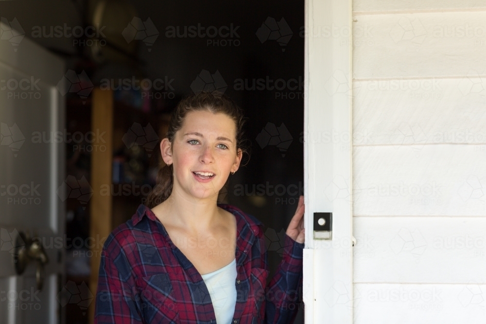 Welcoming teenage girl greeting at front door - Australian Stock Image