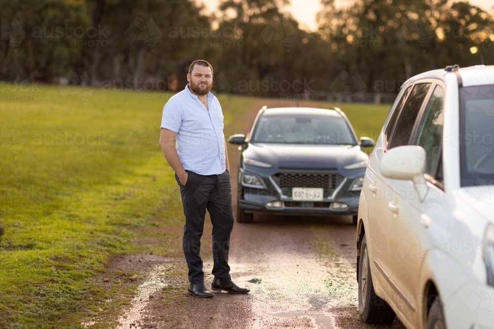 well dressed country bloke standing near car on rural gravel track - Australian Stock Image