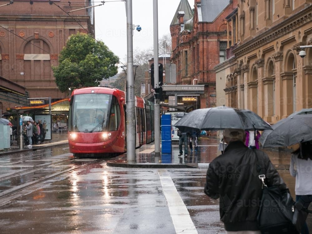 Wet city scene with a tram and pedestrians with umbrellas - Australian Stock Image
