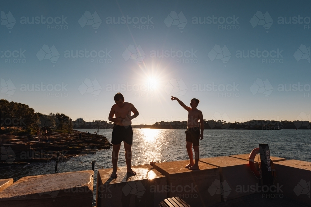 Wet kids standing on ledge at Marrinawi Cove in bright afternoon sunshine - Australian Stock Image