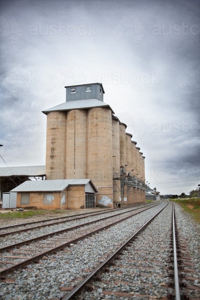 Wheat silo infrastructure beside a train line on an overcast day - Australian Stock Image