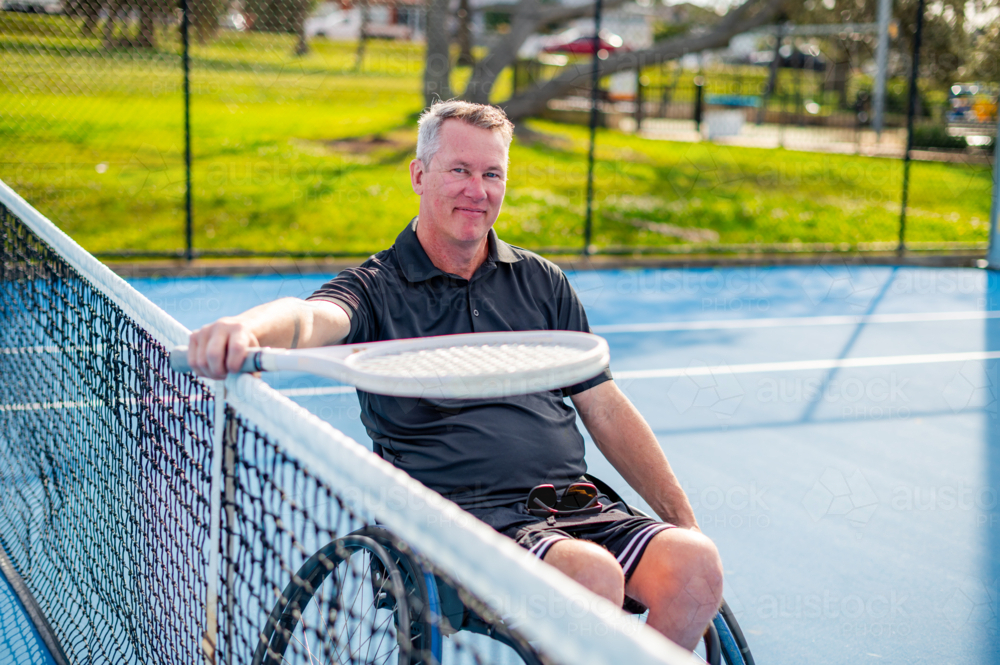 Wheelchair tennis player enjoys a sunny day at the local court with a smile - Australian Stock Image