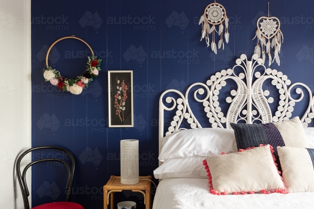 Image of White cane bed head against dark blue wall Austockphoto