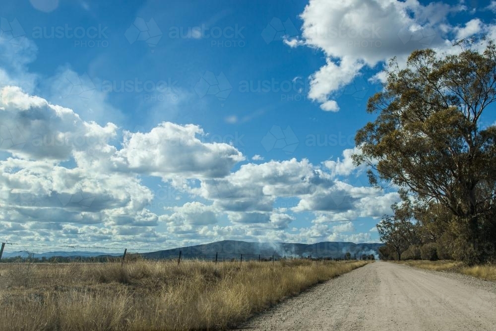 White dirt road with smoke in the distance - Australian Stock Image