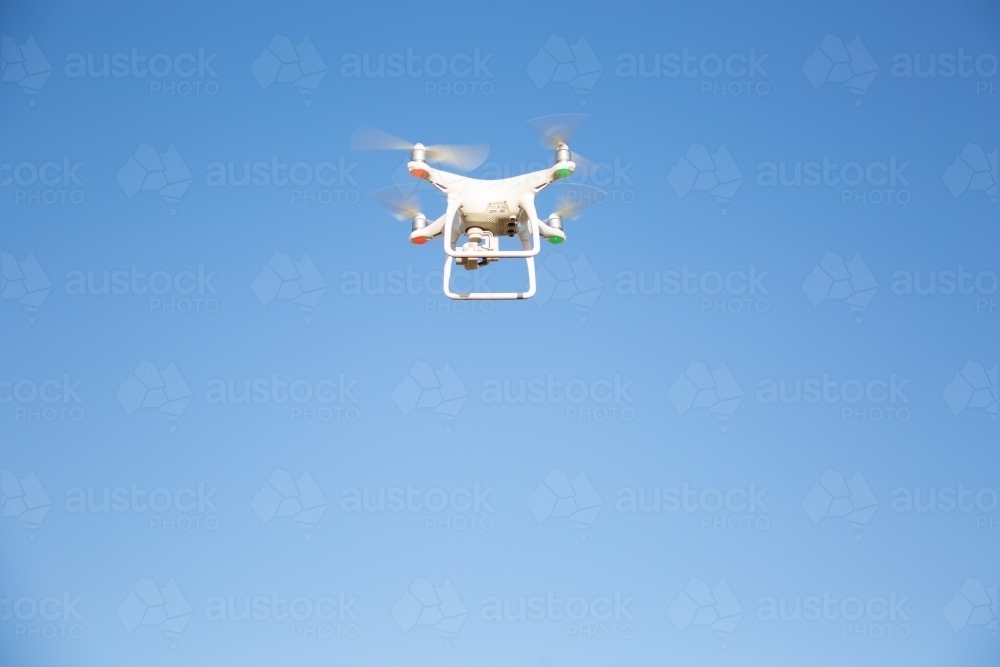 White drone flying in blue sky - Australian Stock Image