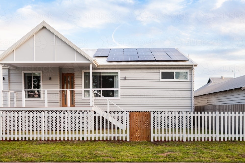 White house with picket fence and solar panels on roof - Australian Stock Image