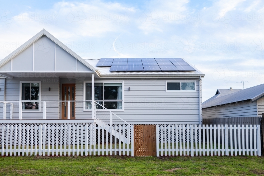 White house with picket fence and solar panels on roof - Australian Stock Image