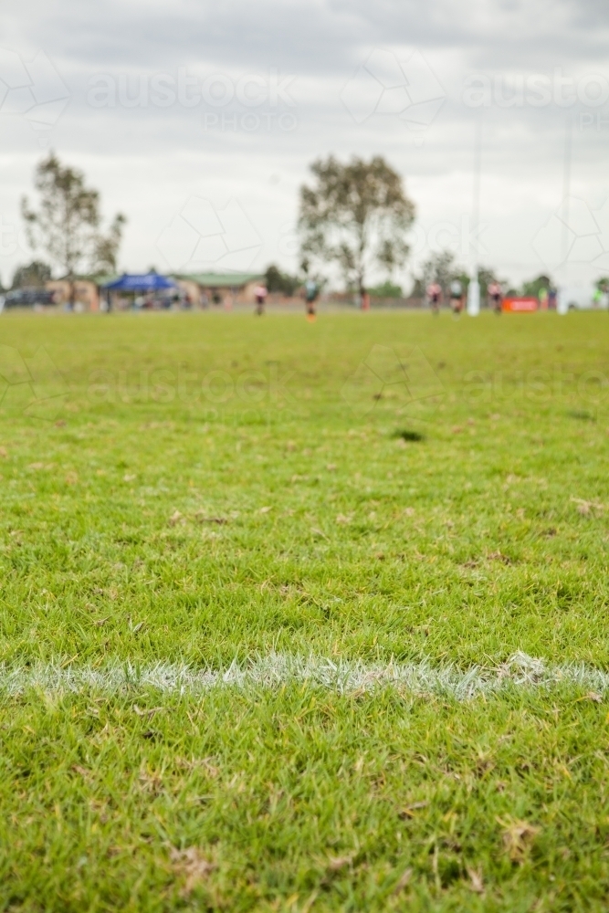 White line on a playing field with out of focus sport players in the background - Australian Stock Image