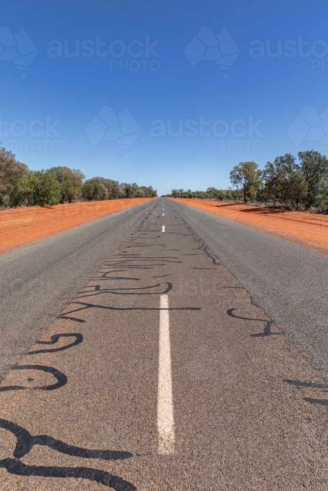 White lines down the middle of the road in Outback NSW with red dirt edges - Australian Stock Image
