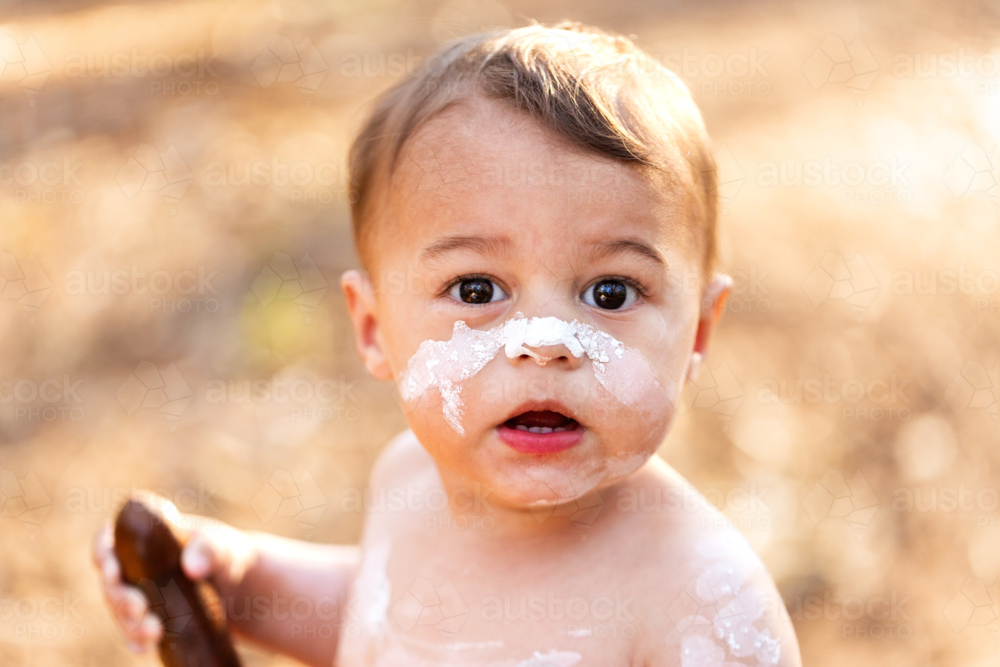 White ochre paint on Aboriginal boys face in natural bushland close up - Australian Stock Image