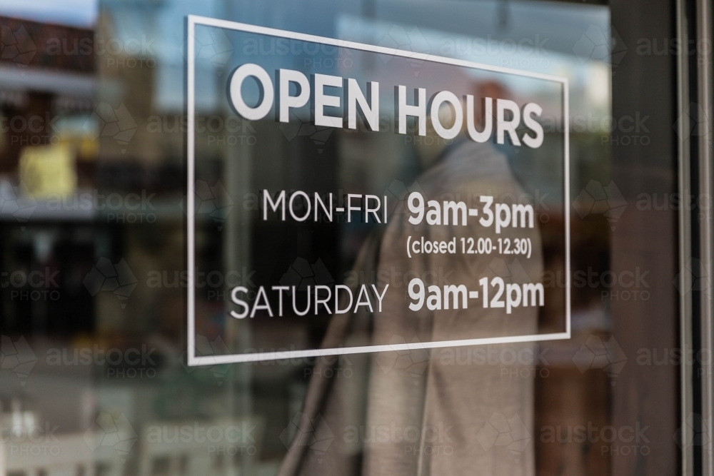 White open hours sign in glass window - Australian Stock Image