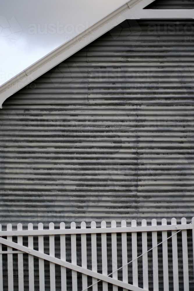 White picket fence leaning against a corrugated iron farm shed : Austockphoto White picket fence leaning against a corrugated iron farm shed - Australian Stock Image