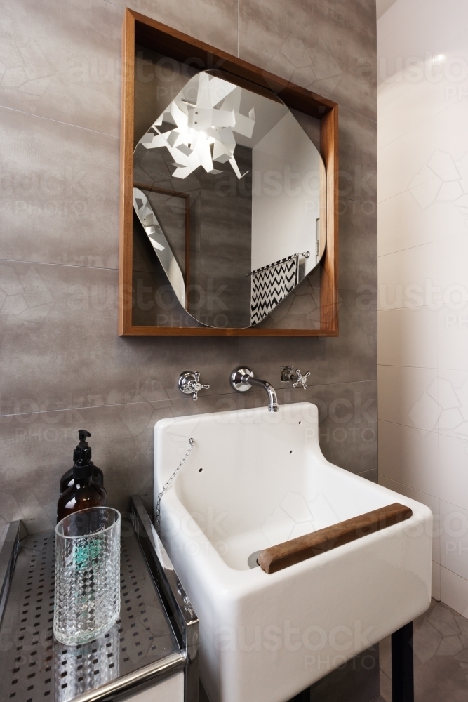 White vintage vanity basin with mirror against grey tiled wall - Australian Stock Image