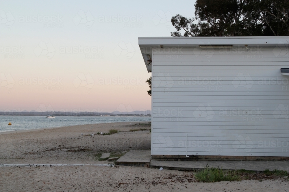 White weatherboard building on the beach at sunset - Australian Stock Image