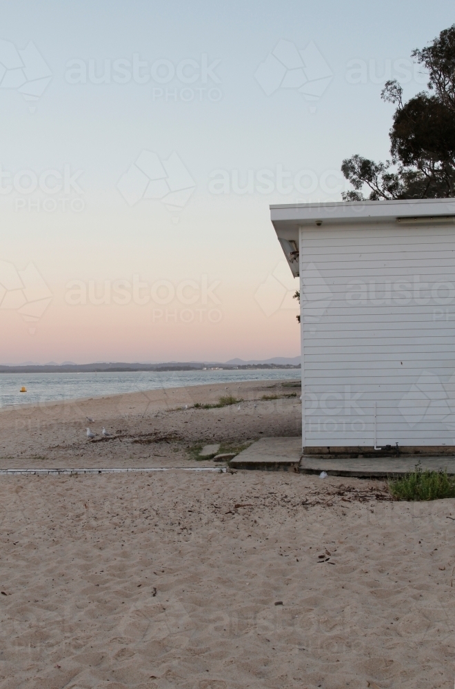 White weatherboard building on the beach at sunset - Australian Stock Image
