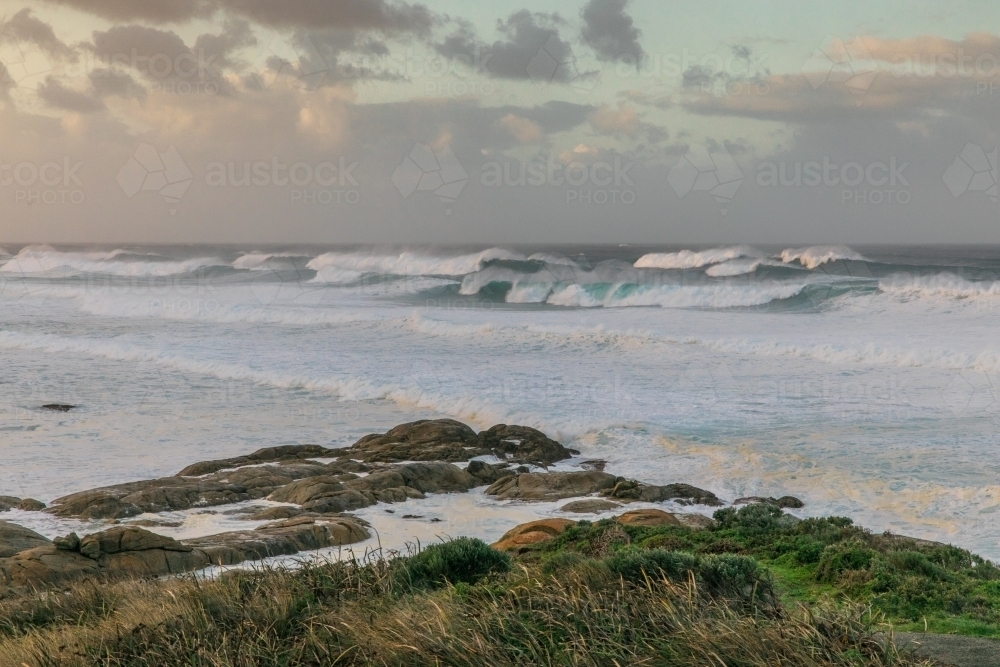 Whitewash waves crashing on coastline as storm brews overhead - Australian Stock Image