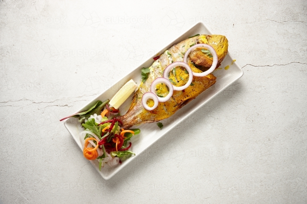 Whole tandoori snapper dish on table - Australian Stock Image
