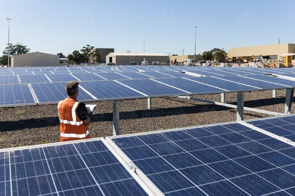 Wide angle of an employee taking notes at a Solar Panel plant - Australian Stock Image