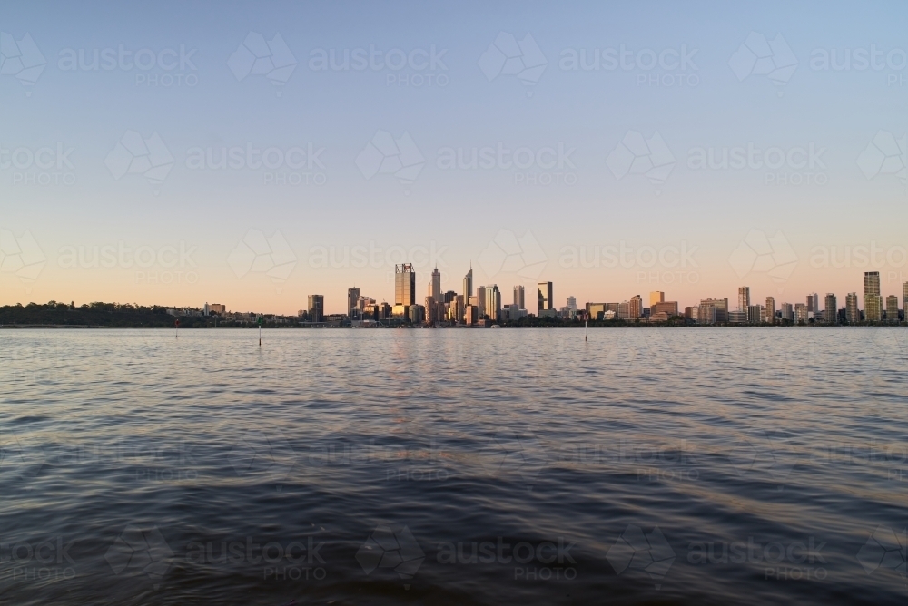 Wide angle view of the Perth city skyline at dusk across the water of the Swan River. - Australian Stock Image