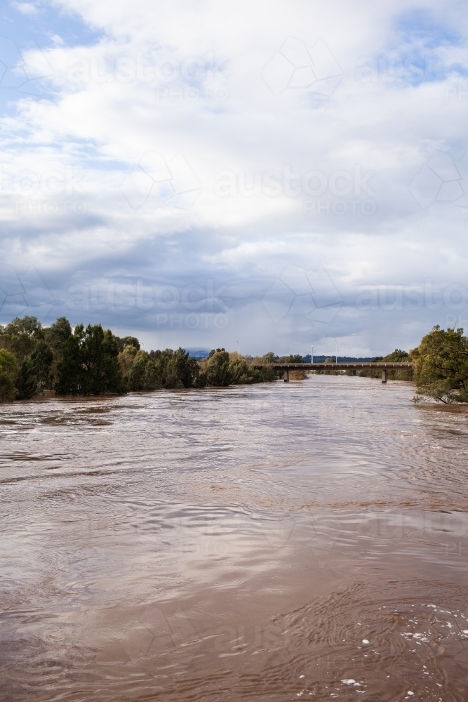 Image of wide brown river full of floodwater during natural disaster