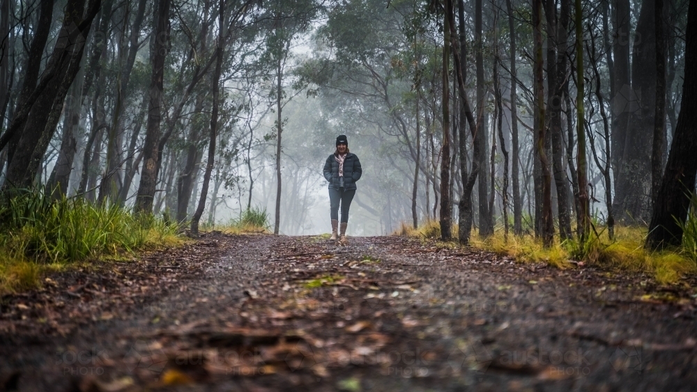 Image of Wide shot of woman walking towards camera on foggy mountain