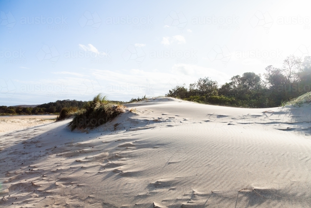 Wind blowing sand over white dunes with sea grass - Australian Stock Image