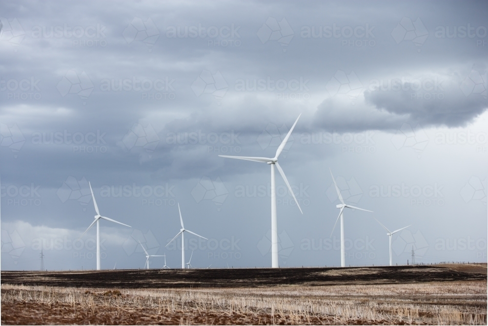 Wind farm in paddock with an incoming storm - Australian Stock Image
