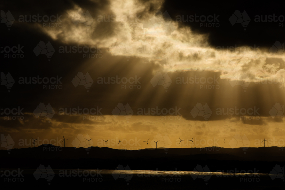 Wind turbines and golden rays and moody clouds - Australian Stock Image