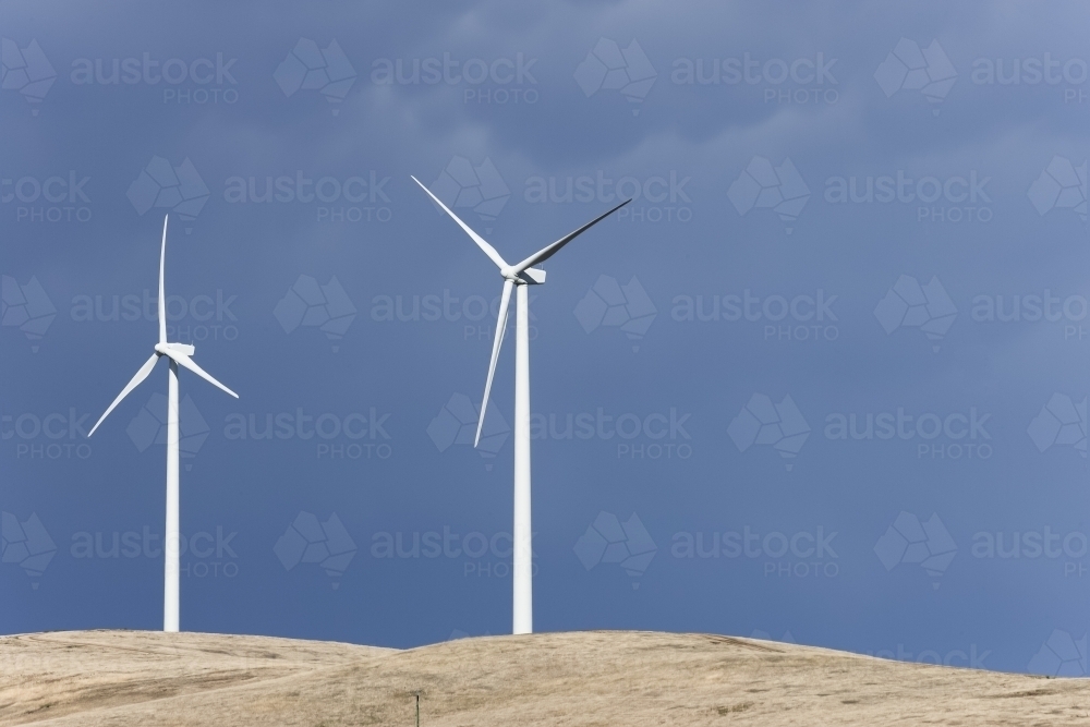 Wind turbines in paddock against storm clouds - Australian Stock Image