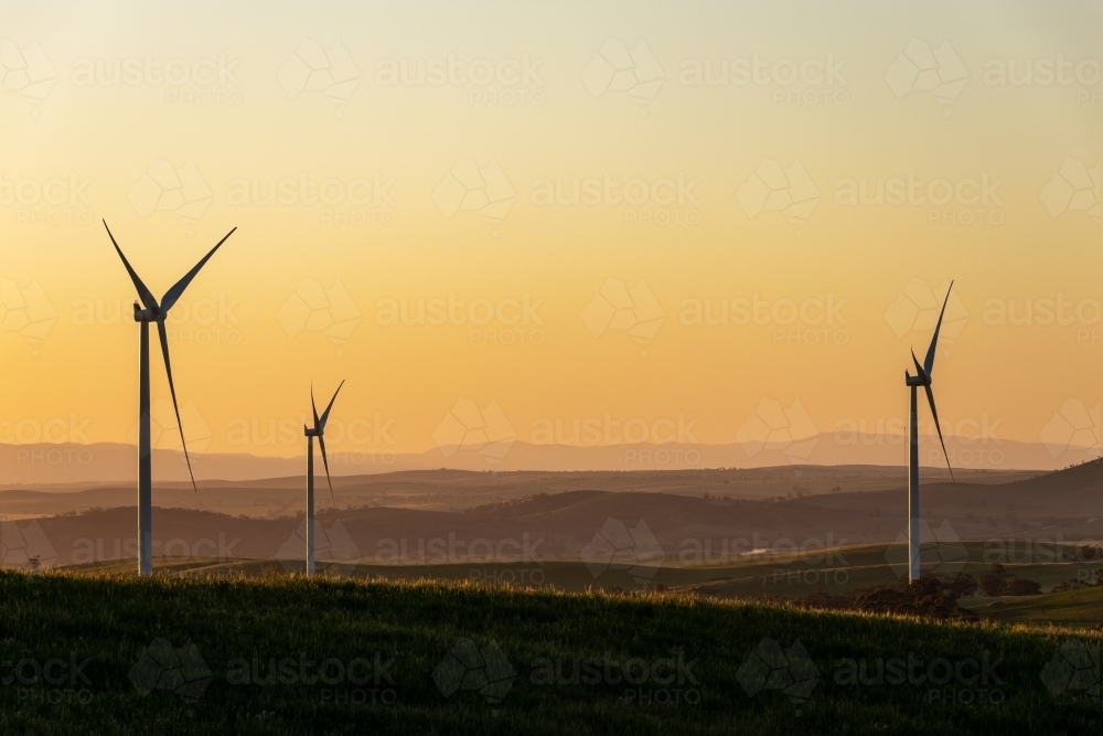 wind turbines in rolling farmland in late afternoon light - Australian Stock Image