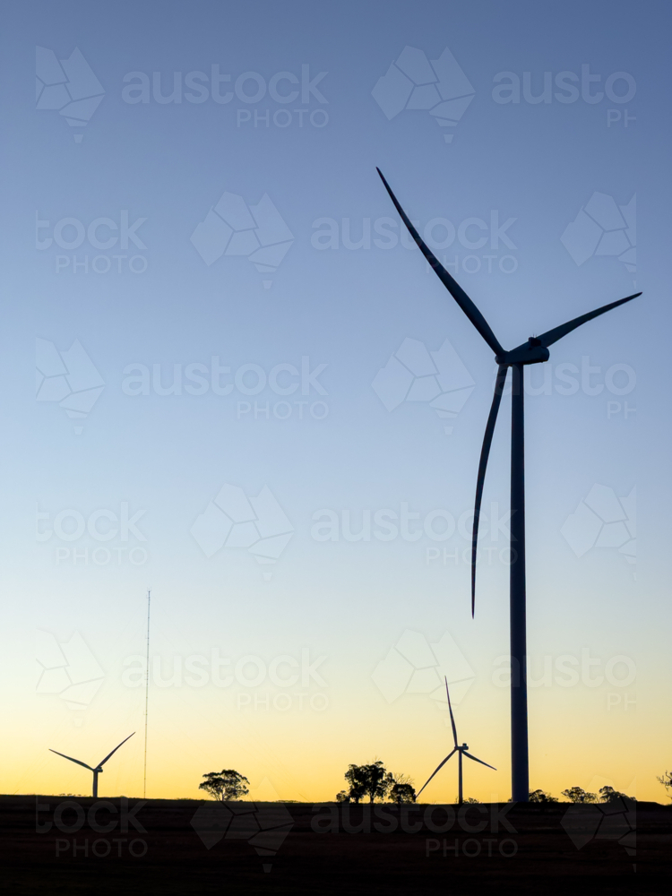 wind turbines in silhouette against fading blue sky at dusk - Australian Stock Image