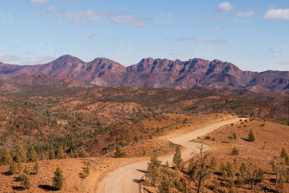 Winding dirt road leading towards rocky mountain range, Flinders Ranges, South Australia - Australian Stock Image