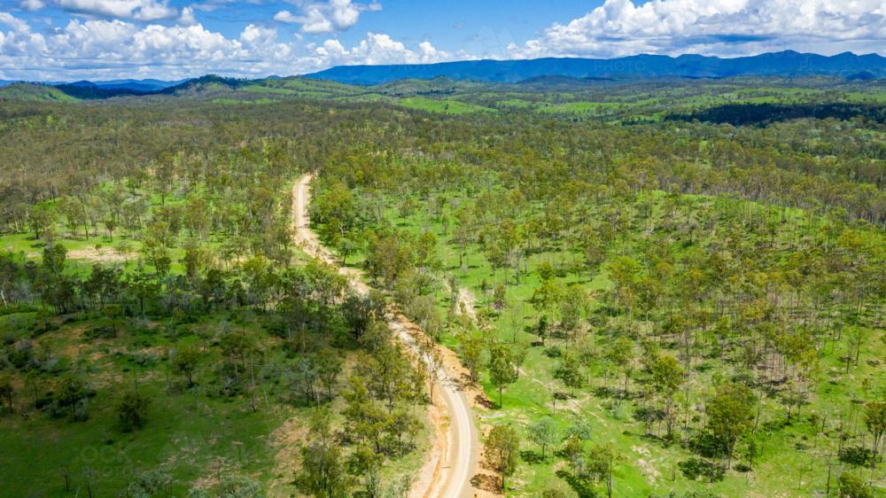 Winding dirt road through forested countryside and mountains - Australian Stock Image