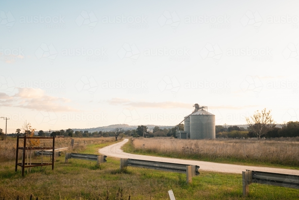 Winding gravel road leading past silos at Coolah, NSW - Australian Stock Image