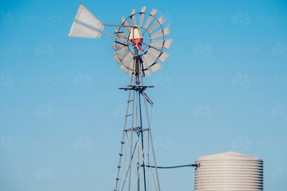 Windmill and water tank with a blue morning sky. - Australian Stock Image