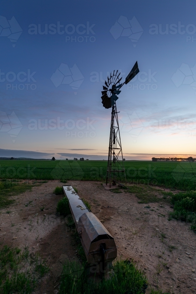 windmill and water trough at dusk - Australian Stock Image