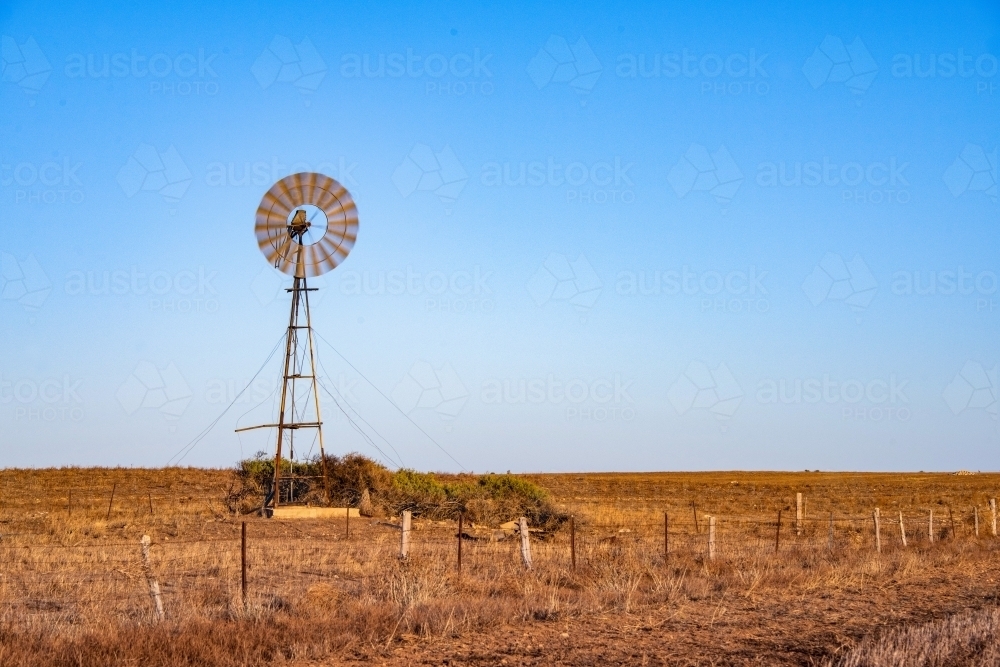 Windmill during the early morning in a dry empty Australian paddock. - Australian Stock Image